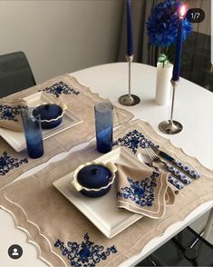 a white table topped with plates and blue vases