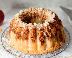 a bundt cake sitting on top of a cooling rack next to an apple slice