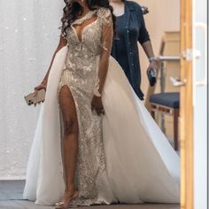 a woman in a white dress is walking down the aisle with another woman behind her