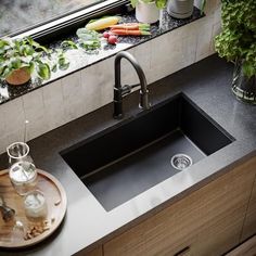 a kitchen sink sitting under a window next to a cutting board with vegetables on it