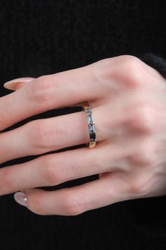 a woman's hand wearing a gold ring with two diamonds on it and a black background