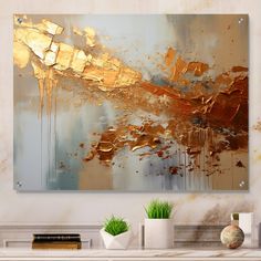 an abstract painting in gold and silver on a white wall above a fireplace mantel