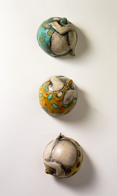 three ceramic balls with designs on them sitting next to each other in front of a white wall