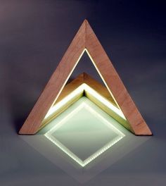 an illuminated wooden triangle on a reflective surface