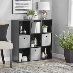 a black and white bookcase with four bins in front of a painting on the wall