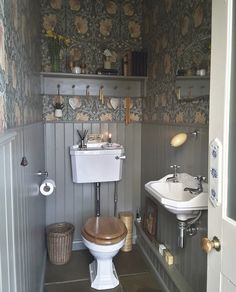 a bathroom with a toilet, sink and shelves on the wall next to each other