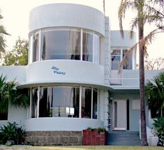 a large white building with palm trees in the foreground and stairs leading up to it