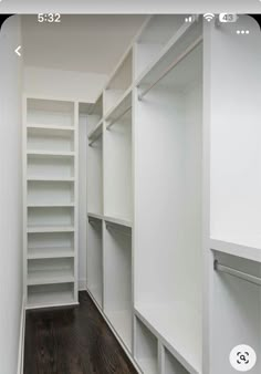 an empty walk - in closet with white shelving and wood flooring is shown