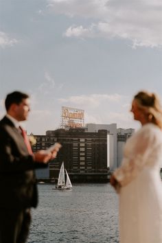 a man and woman standing next to each other in front of a body of water