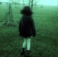 a woman standing in the grass with her back to the camera