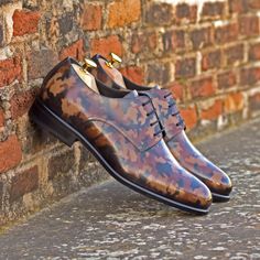 a pair of brown shoes sitting on top of a brick wall