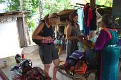 two women standing in front of a table with bags on it and clothes hanging up to dry