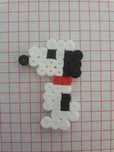 two white and black sheep made out of buttons on a piece of paper with red pins