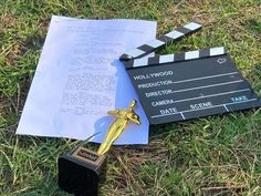 a movie clapper and award laying on the grass