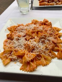 a white plate topped with pasta covered in cheese