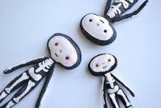 three handmade dolls made to look like skeletons and skeleton heads on a white surface