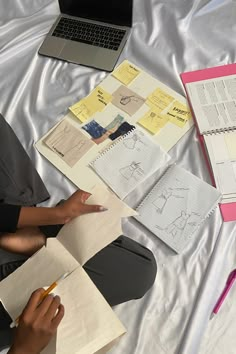 a person sitting on a bed with notebooks and papers