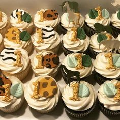 cupcakes with white frosting and gold decorations are arranged in a box on the table