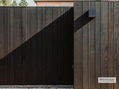 a wooden fence with a brick building in the back ground and two doors on each side