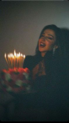 a woman holding a birthday cake with lit candles