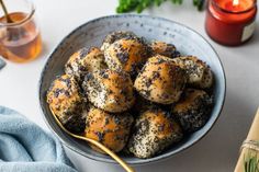 a bowl filled with sesame seed bagels next to a glass of tea and a candle