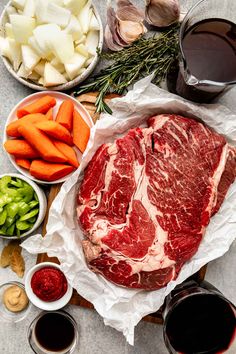 raw meat, vegetables and sauces laid out on a table to make a steak dinner