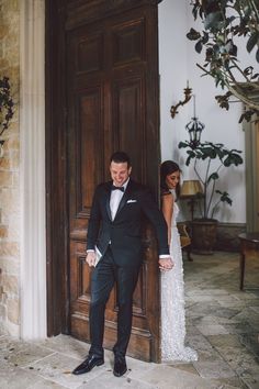 a man in a tuxedo standing next to a door