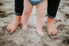 a toddler standing in the sand with his bare feet