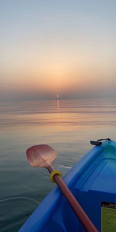 the sun is setting over the ocean with a paddle in it's oar