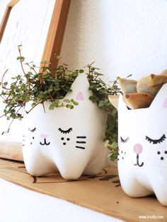 two white cat planters sitting on top of a wooden shelf next to a mirror