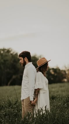 a man and woman standing in tall grass