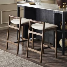 two stools sitting next to each other in front of a counter with vases on it