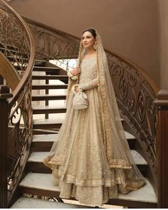 a woman in a bridal gown standing on the stairs with her handbag and purse