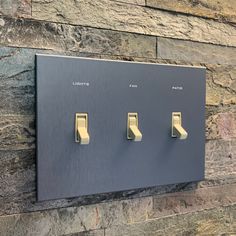 three light switch plates mounted on a stone wall