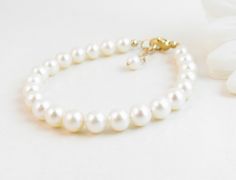 "A classic real freshwater pearl bracelet for newborn, infant, baby, child, little girl, tween or teen. This keepsake bracelet is created with Grade-A 5.5mm round freshwater pearls and a 14K gold-filled oval lobster clasp with a 1/2\" \"Grow with Me\" extender chain. Arrives packaged in my signature high-quality reusable canvas gift bag. Beautiful and ready for gift giving. S I Z I N G . G U I D E The bracelet should be 3/4\" larger than her snug wrist measurement. If you are unable to measure, Elegant Adjustable Pearl Bracelet For Baptism, Elegant Pearl Jewelry For Baptism, Elegant Pearl White Jewelry For Baptism, Elegant Hypoallergenic Rosary Bracelet For Baptism, Classic Adjustable Jewelry For First Communion, Classic Adjustable Hypoallergenic Pearl Bracelet, Elegant Adjustable Bracelets For Baptism, Elegant Adjustable Bracelet For Baptism, Elegant Pearl Bracelet For First Communion