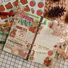 an open planner book sitting on top of a table next to pine cones and other items