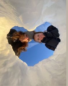 two people standing in the middle of a heart shaped hole