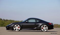 a black sports car parked on the side of an empty parking lot with trees in the background