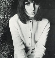 black and white photograph of a woman sitting on the ground with her hands in her pockets