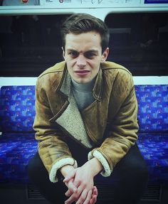 a man sitting on a bus with his hands crossed