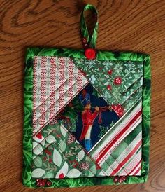 an ornament hanging on a wooden table with green and red ornaments around it