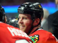 a hockey player wearing a black helmet and red jersey is standing next to another player