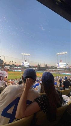 two people sitting in the stands at a baseball game, one is covering his face