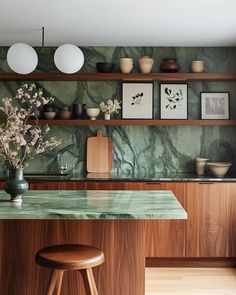 a green marble counter top in a kitchen with wooden shelves and stools next to it