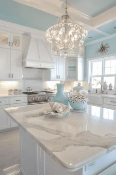 a white kitchen with marble counter tops and an island in front of the stove top