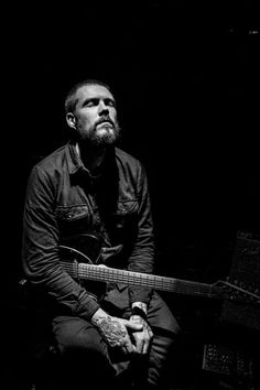 a black and white photo of a man holding a guitar