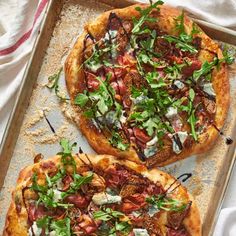 two pizzas with various toppings sitting on top of a pan next to each other