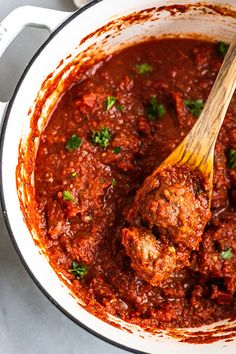 meatballs and sauce in a pot with a wooden spoon