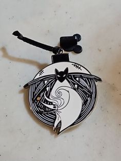 a black and white cat sitting on top of a table next to a key chain