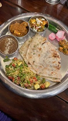 a silver plate topped with different types of food next to bowls of sauces and condiments